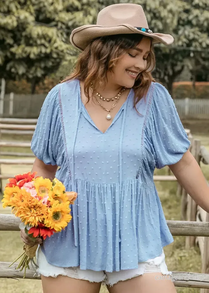 Plus size blus i ljusblå swiss dot – feminin med knytning och mjukt fall Plus size blus i ljusblå swiss dot – feminin med knytning och mjukt fall